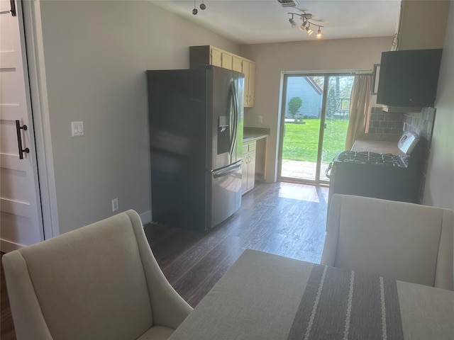 kitchen with wood finished floors, rail lighting, baseboards, backsplash, and stainless steel fridge with ice dispenser