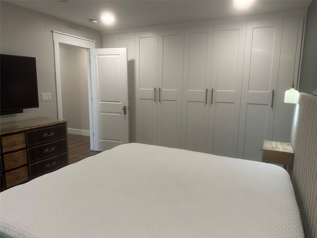 bedroom with a closet, baseboards, and dark wood-style floors