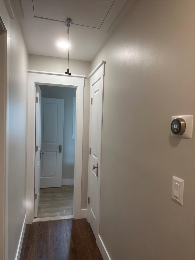 corridor featuring baseboards and dark wood finished floors