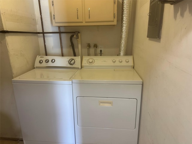 washroom featuring electric panel, washing machine and clothes dryer, and cabinet space