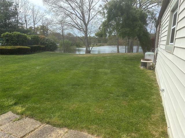 view of yard with a water view and central AC unit