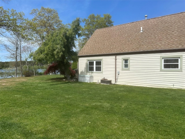 rear view of house featuring a yard, a shingled roof, and central AC