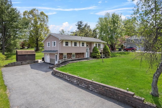 raised ranch featuring aphalt driveway, a storage unit, a garage, an outbuilding, and a front yard