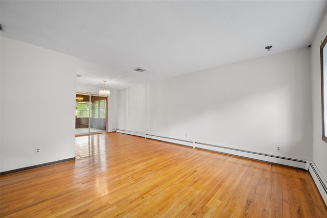 empty room with baseboard heating, an inviting chandelier, visible vents, and wood finished floors