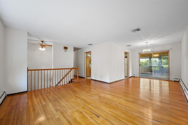 spare room with ceiling fan with notable chandelier, light wood-type flooring, visible vents, a baseboard radiator, and baseboard heating