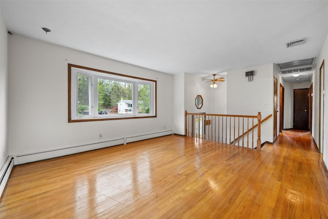 empty room featuring a baseboard heating unit, visible vents, and wood finished floors