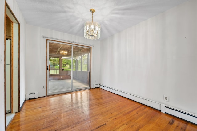 spare room featuring a baseboard radiator, baseboard heating, a chandelier, and wood finished floors