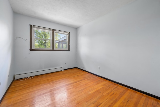 spare room featuring baseboards, a baseboard radiator, and light wood-type flooring