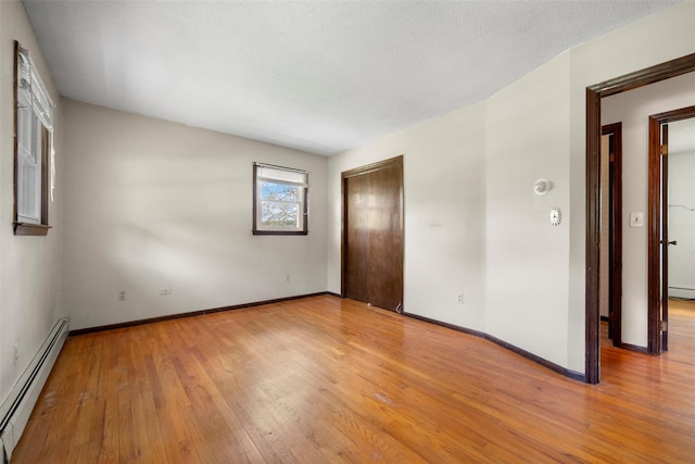 empty room featuring baseboards, baseboard heating, and wood finished floors