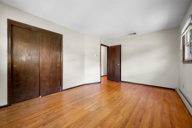 unfurnished bedroom featuring a baseboard radiator, a closet, baseboards, visible vents, and light wood-type flooring
