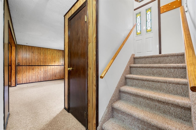 stairs featuring wooden walls and carpet