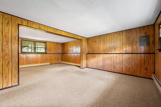 unfurnished room with carpet flooring, wood walls, baseboards, and a baseboard radiator