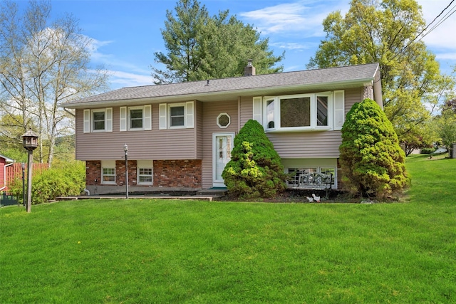 raised ranch featuring a front lawn, brick siding, and a chimney