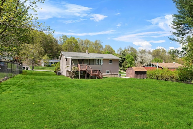 back of house featuring a storage shed, an outdoor structure, a yard, stairway, and a wooden deck