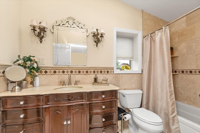 full bath with toilet, tile walls, vanity, shower / tub combo, and a wainscoted wall