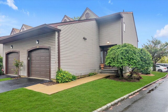 view of side of property with a lawn, a garage, and driveway