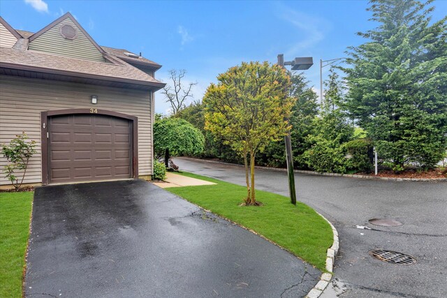 view of property exterior with driveway, roof with shingles, and a garage