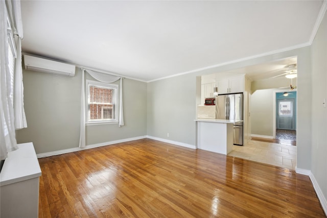 43-28 196th St, Flushing, NY 11358 - unfurnished living room featuring a ceiling fan, light wood-type flooring, a healthy amount of sunlight, and a wall mounted air conditioner