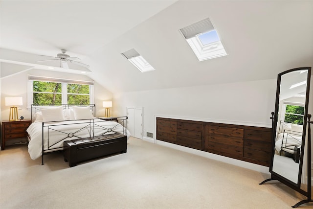 bedroom featuring a skylight, vaulted ceiling, light carpet, and ceiling fan
