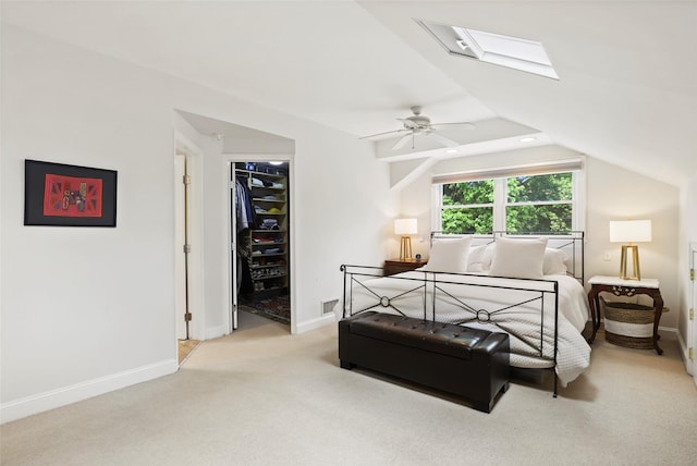bedroom featuring a skylight, carpet flooring, baseboards, a spacious closet, and vaulted ceiling