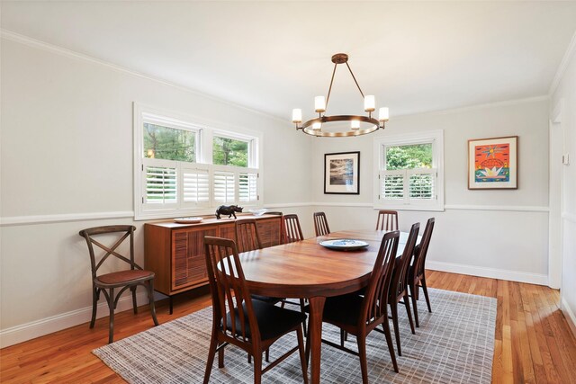 dining space with a chandelier, plenty of natural light, crown molding, light wood-style flooring, and baseboards