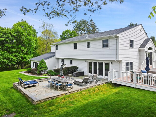 rear view of property featuring a patio area, a wooden deck, a yard, and roof with shingles