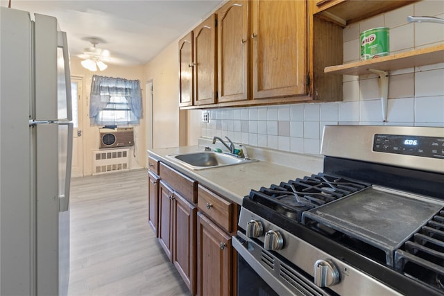 kitchen with decorative backsplash, gas range, a sink, light countertops, and freestanding refrigerator