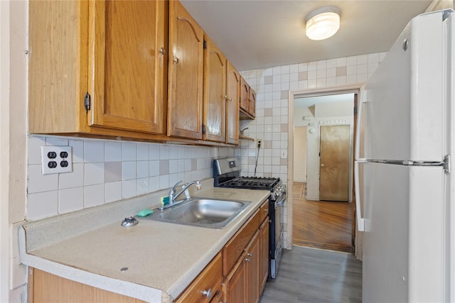 kitchen with a sink, gas stove, light countertops, light wood-style flooring, and freestanding refrigerator