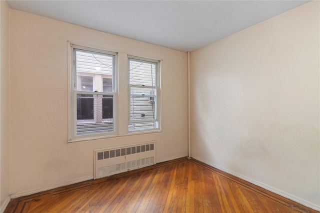 unfurnished room with radiator, baseboards, and hardwood / wood-style flooring