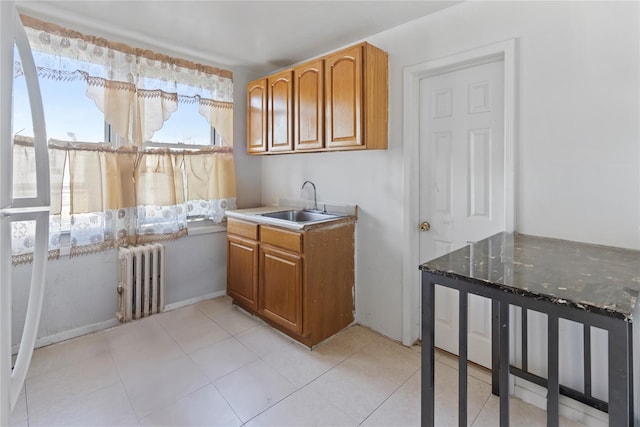 kitchen featuring a sink, radiator, light tile patterned floors, and brown cabinetry