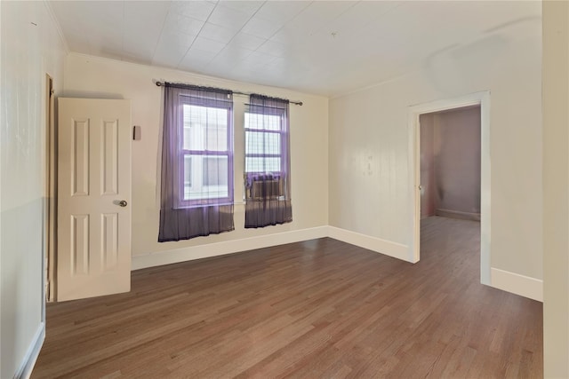 empty room with baseboards, crown molding, and wood finished floors