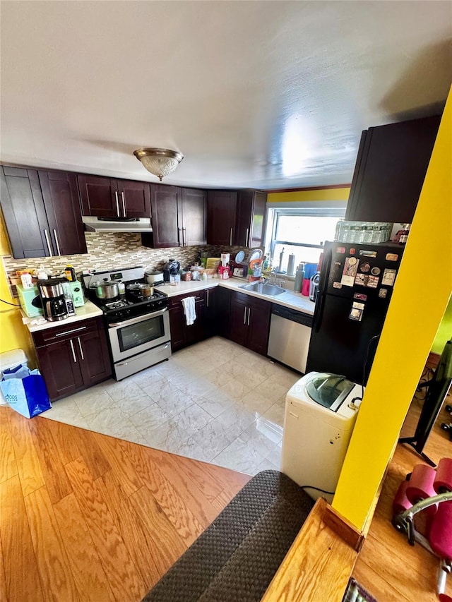 kitchen featuring light countertops, under cabinet range hood, backsplash, and stainless steel appliances