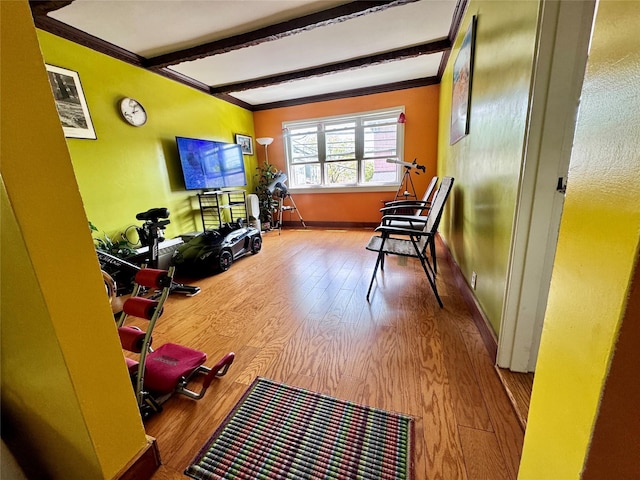 sitting room with wood finished floors, ornamental molding, and beam ceiling