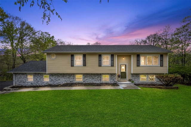 split foyer home with stone siding and a front lawn