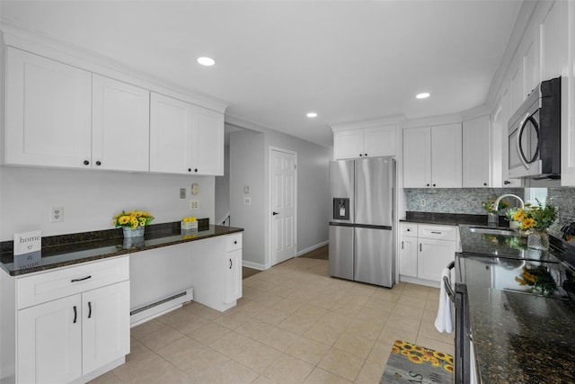 kitchen featuring white cabinetry, a baseboard heating unit, a sink, appliances with stainless steel finishes, and backsplash
