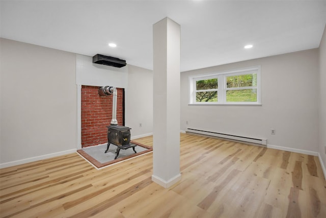unfurnished living room featuring baseboards, a baseboard heating unit, wood finished floors, and a wood stove