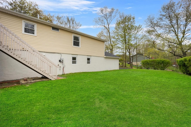 back of property featuring stucco siding, a yard, and stairway