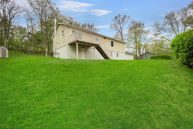 back of property with a storage unit, stairs, a deck, an outdoor structure, and a yard