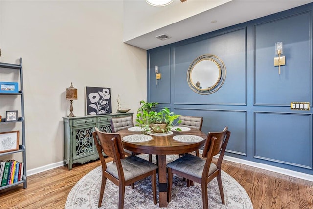 dining area with wood finished floors, baseboards, and a decorative wall
