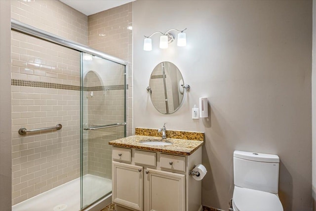 bathroom with a shower stall, toilet, and vanity