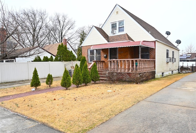 bungalow with fence, covered porch, and roof with shingles