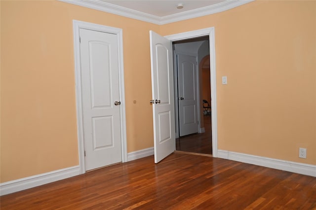 unfurnished bedroom with baseboards, arched walkways, wood finished floors, and ornamental molding