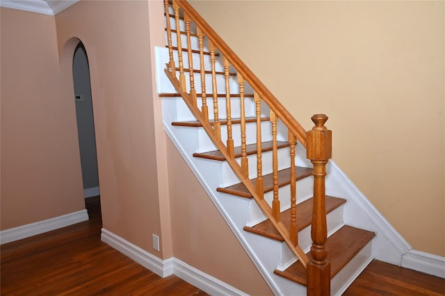 stairs featuring baseboards, arched walkways, crown molding, and wood finished floors