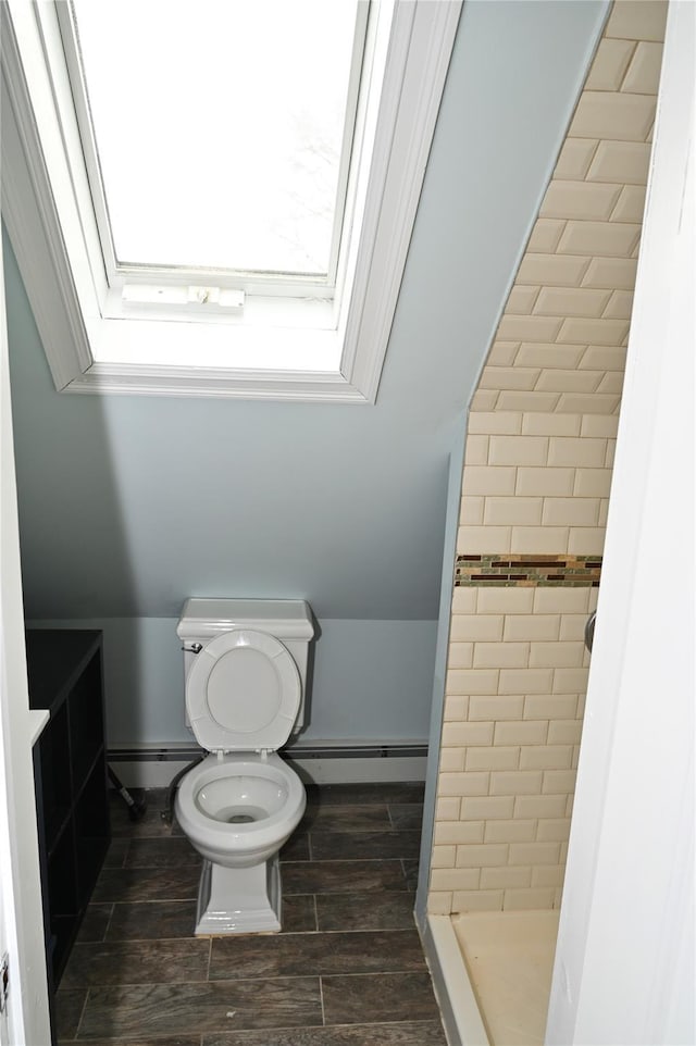 full bath with a skylight, a stall shower, baseboards, a baseboard radiator, and toilet