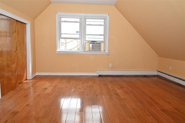 additional living space featuring baseboards, cooling unit, vaulted ceiling, and hardwood / wood-style floors