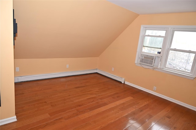 additional living space featuring baseboards, a baseboard radiator, cooling unit, lofted ceiling, and hardwood / wood-style floors