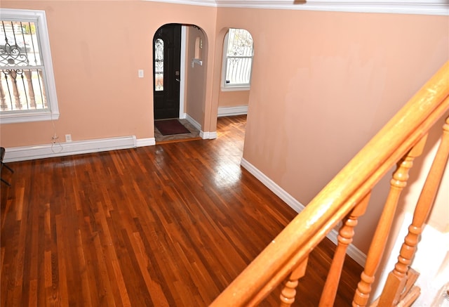 entrance foyer with arched walkways, baseboards, dark wood-style floors, and ornamental molding