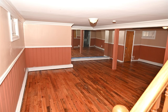 below grade area featuring ornamental molding, a wainscoted wall, baseboard heating, and hardwood / wood-style floors