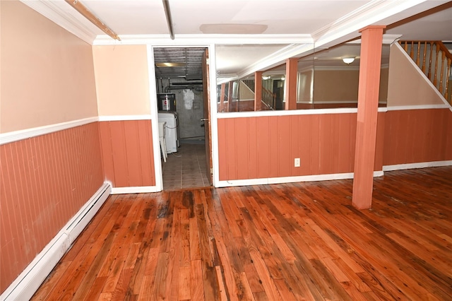 unfurnished room featuring wainscoting, stairway, a baseboard heating unit, washer / dryer, and hardwood / wood-style floors