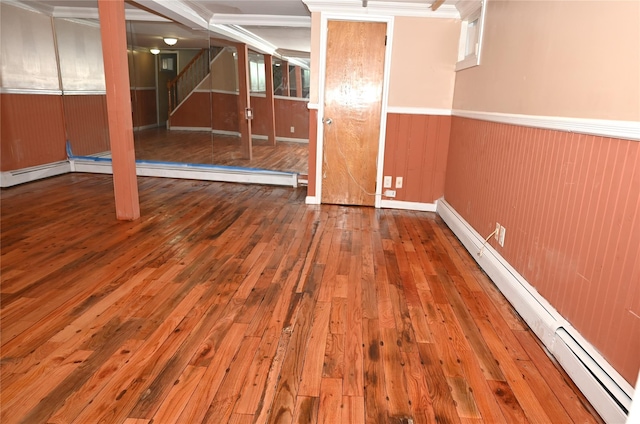 basement with a baseboard radiator, a wainscoted wall, hardwood / wood-style flooring, and stairway